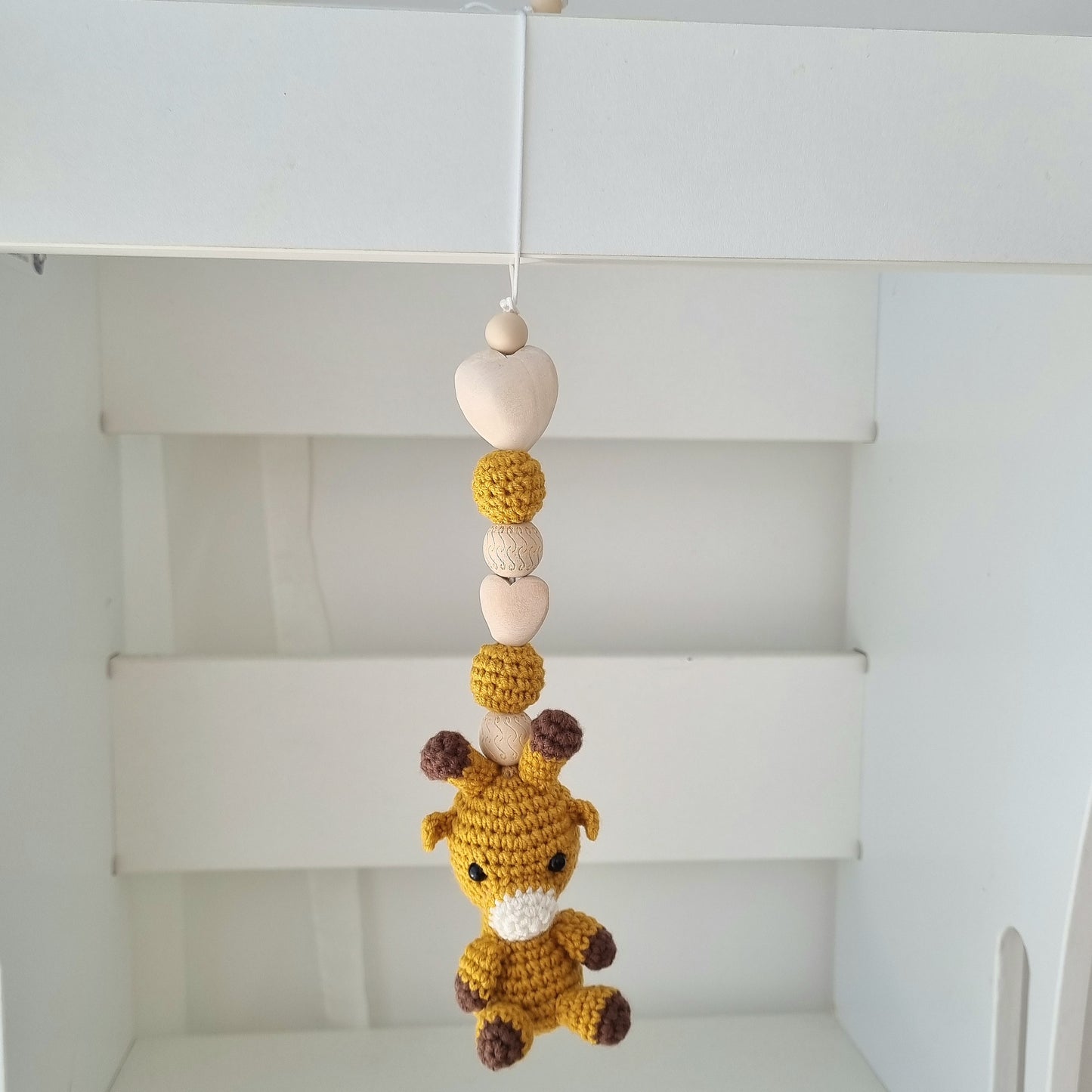 Ein handgefertigter Maxi-Cosi-Anhänger aus bunten Perlen, Häkeltier und Holzelementen, der unterwegs für Unterhaltung sorgt. Die verschiedenen Farben und Texturen machen das Reisen mit dem Baby nie langweilig. Ideal für Maxi-Cosi, Kinderwagen oder Bettchen.