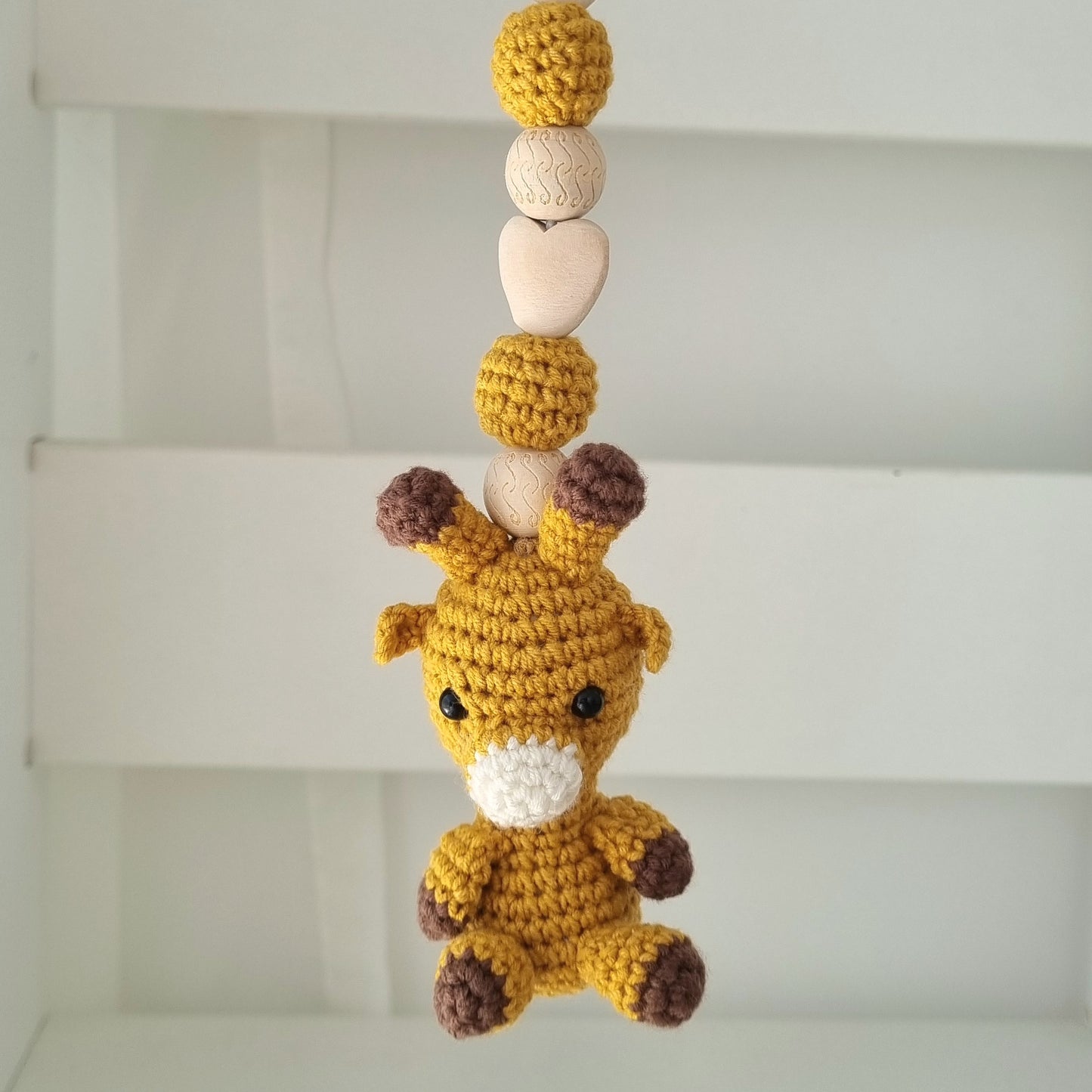 Ein handgefertigter Maxi-Cosi-Anhänger aus bunten Perlen, Häkeltier und Holzelementen, der unterwegs für Unterhaltung sorgt. Die verschiedenen Farben und Texturen machen das Reisen mit dem Baby nie langweilig. Ideal für Maxi-Cosi, Kinderwagen oder Bettchen.