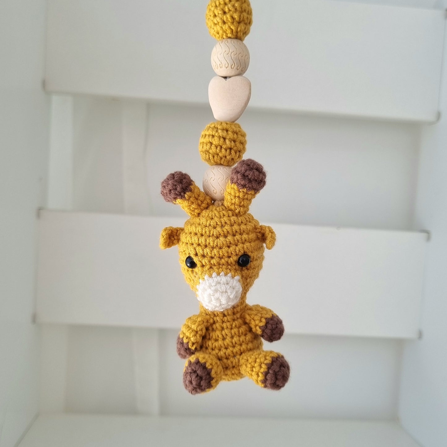 Ein handgefertigter Maxi-Cosi-Anhänger aus bunten Perlen, Häkeltier und Holzelementen, der unterwegs für Unterhaltung sorgt. Die verschiedenen Farben und Texturen machen das Reisen mit dem Baby nie langweilig. Ideal für Maxi-Cosi, Kinderwagen oder Bettchen.