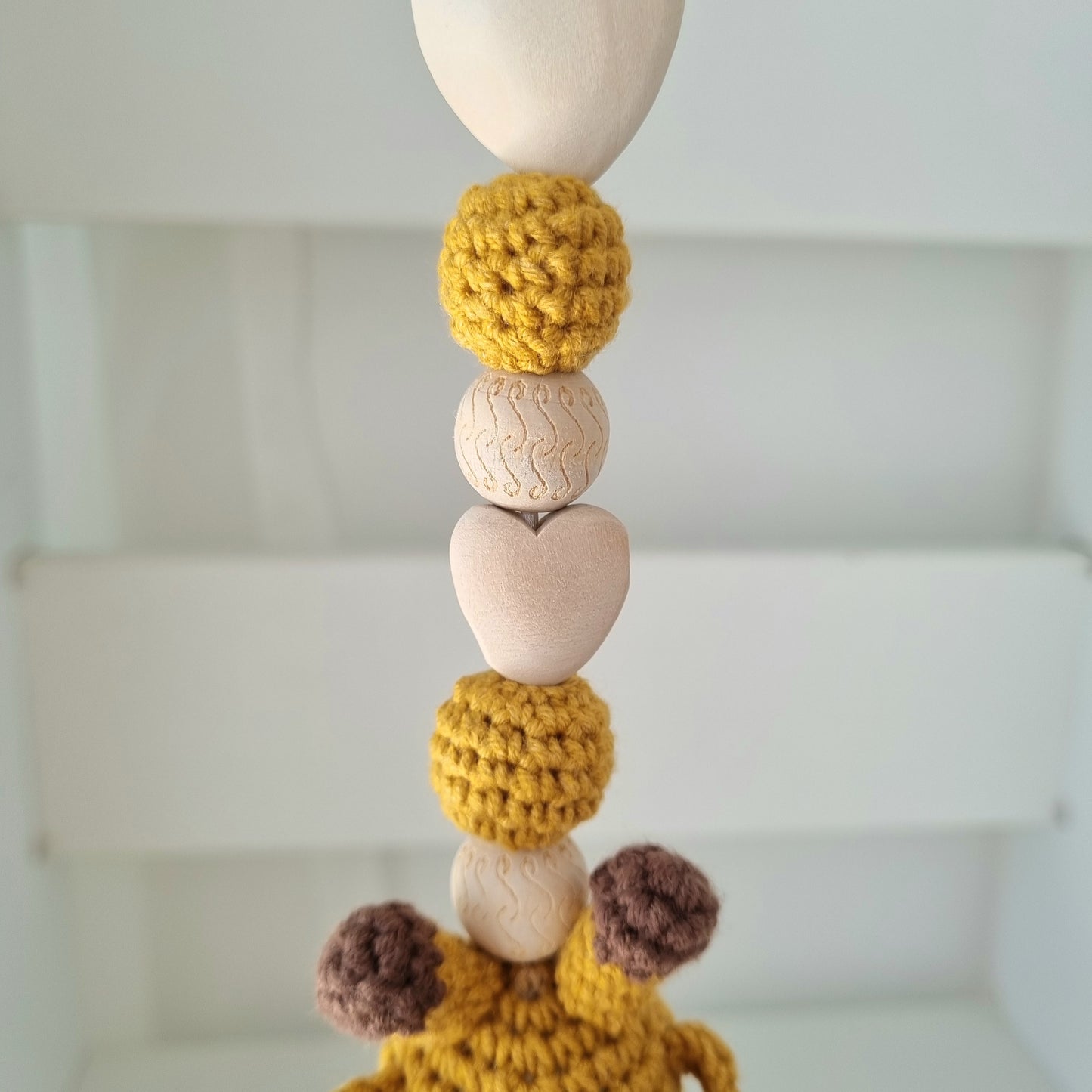 Ein handgefertigter Maxi-Cosi-Anhänger aus bunten Perlen, Häkeltier und Holzelementen, der unterwegs für Unterhaltung sorgt. Die verschiedenen Farben und Texturen machen das Reisen mit dem Baby nie langweilig. Ideal für Maxi-Cosi, Kinderwagen oder Bettchen.