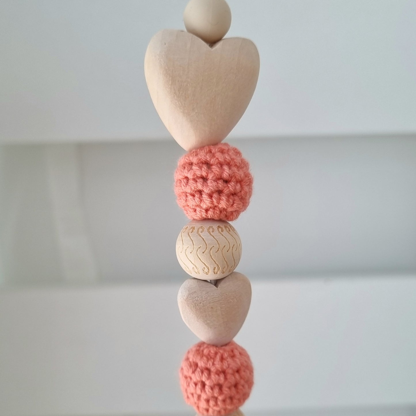 Ein handgefertigter Maxi-Cosi-Anhänger aus bunten Perlen, Häkeltier und Holzelementen, der unterwegs für Unterhaltung sorgt. Die verschiedenen Farben und Texturen machen das Reisen mit dem Baby nie langweilig. Ideal für Maxi-Cosi, Kinderwagen oder Bettchen.