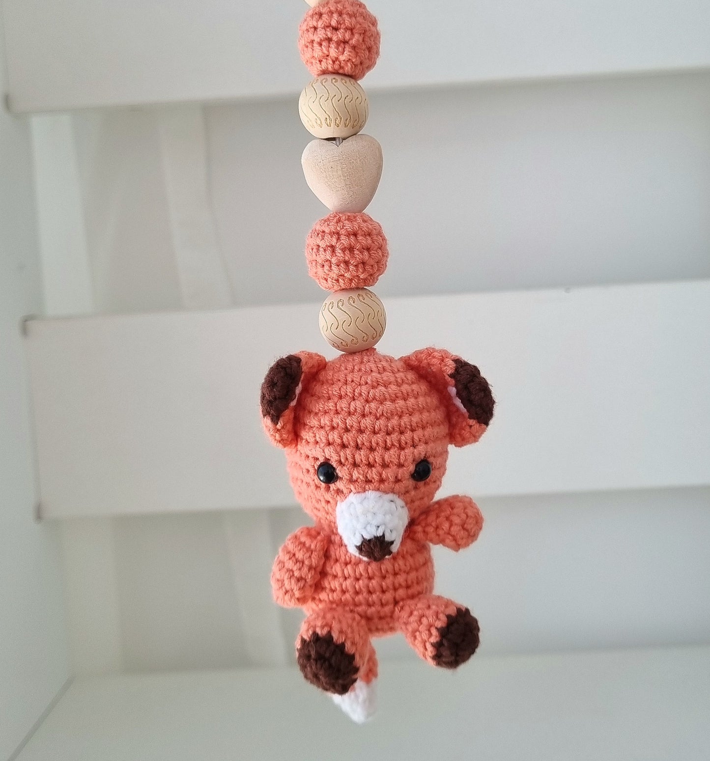 Ein handgefertigter Maxi-Cosi-Anhänger aus bunten Perlen, Häkeltier und Holzelementen, der unterwegs für Unterhaltung sorgt. Die verschiedenen Farben und Texturen machen das Reisen mit dem Baby nie langweilig. Ideal für Maxi-Cosi, Kinderwagen oder Bettchen.Marchon