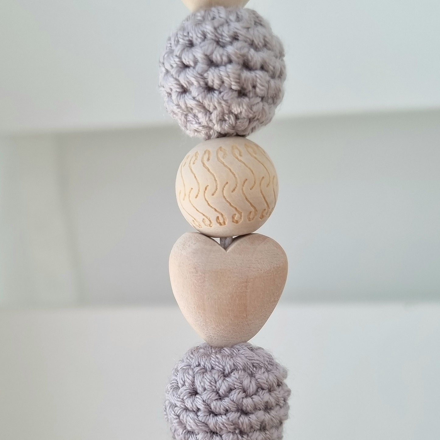 Ein handgefertigter Maxi-Cosi-Anhänger aus bunten Perlen, Häkeltier und Holzelementen, der unterwegs für Unterhaltung sorgt. Die verschiedenen Farben und Texturen machen das Reisen mit dem Baby nie langweilig. Ideal für Maxi-Cosi, Kinderwagen oder Bettchen.