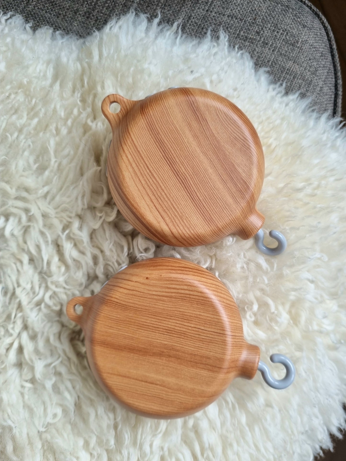 Mobile Spieluhr mit Oberfläche in Holzoptik, die beruhigende Melodien abspielt, ideal für das Kinderbett oder den Kinderwagen. Ausgestattet mit bunten Tierfiguren und sanften Bewegungen, fördert sie die visuelle und auditive Stimulation des Babys. Einfach zu befestigen und batteriebetrieben für eine unkomplizierte Nutzung. Perfekt, um Babys in den Schlaf zu wiegen und eine natürliche, beruhigende Umgebung zu schaffen.