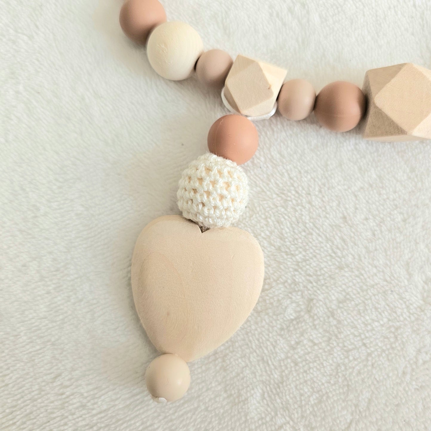 Eine handgefertigte Kinderwagenkette aus bunten Perlen und Häkelelementen. Die lebendigen Farben und unterschiedlichen Texturen bieten Ihrem Baby unterwegs Unterhaltung und fördern die Sinne. Ideal zur Befestigung am Kinderwagen.