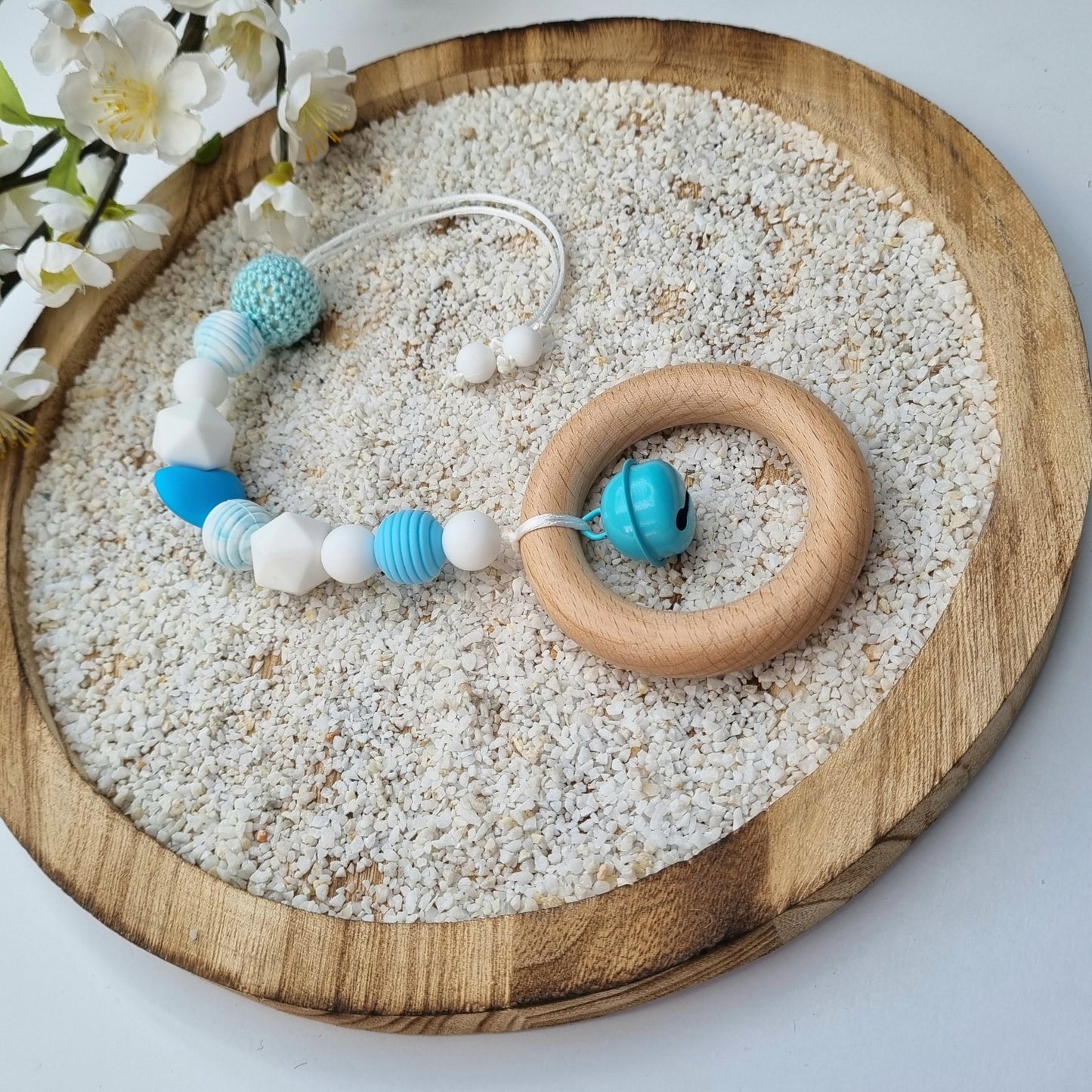 Ein handgefertigter Maxi-Cosi-Anhänger aus bunten Perlen, Holzelementen und Glocke, der unterwegs für Unterhaltung sorgt. Die verschiedenen Farben und Texturen machen das Reisen mit dem Baby nie langweilig. Ideal für Maxi-Cosi, Kinderwagen oder Bettchen.